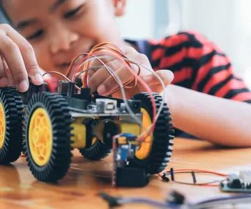 Child smiles while building a robotic vehicle